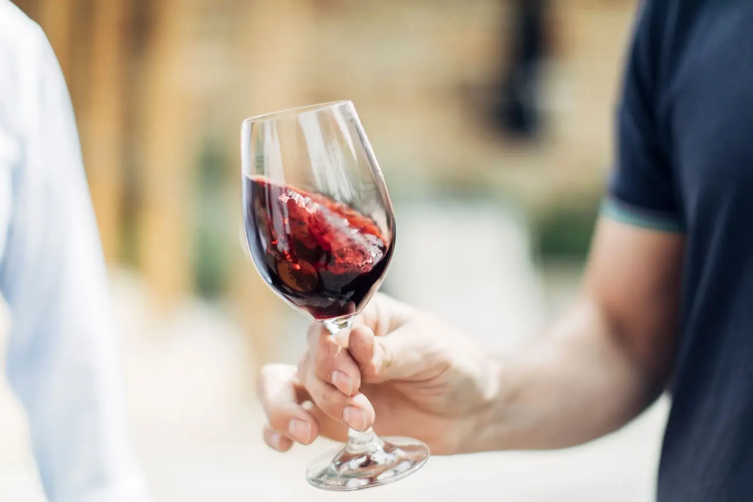a hand holding a glass of red wine