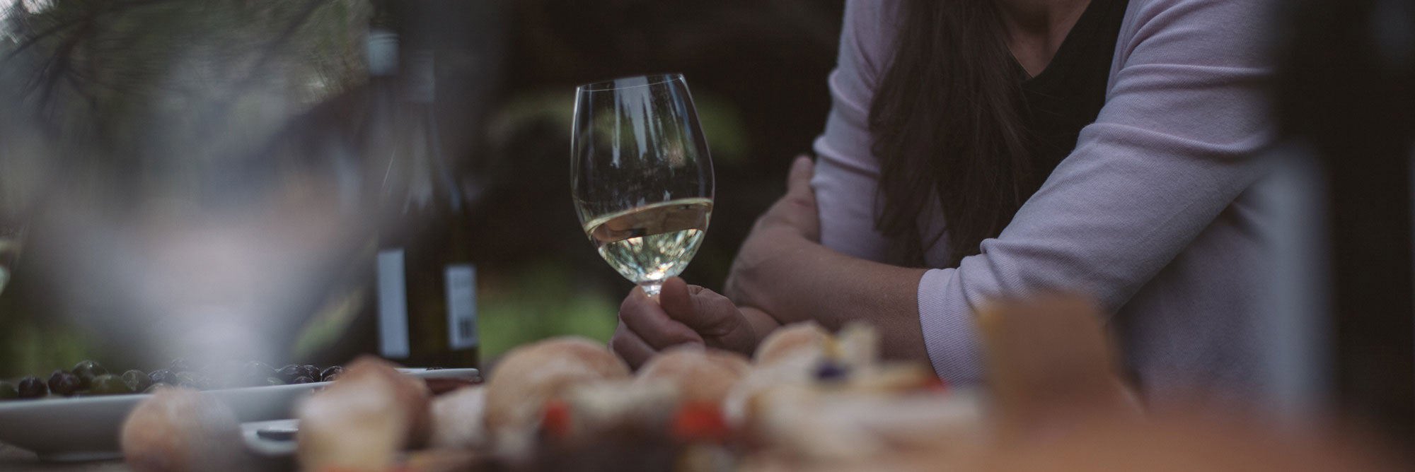 Woman with white wine glass at table with food