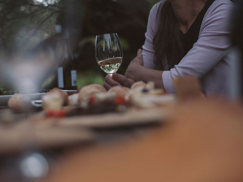 Woman with white wine glass at table with food