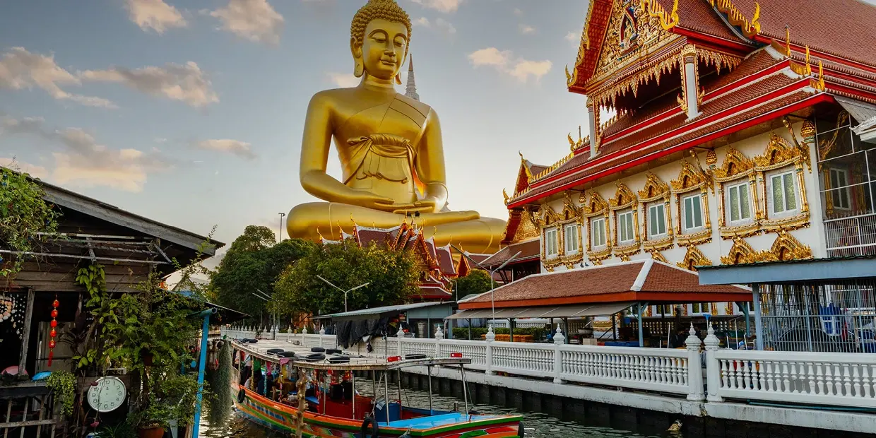 A large gold statue of a buddha sitting on a body of water