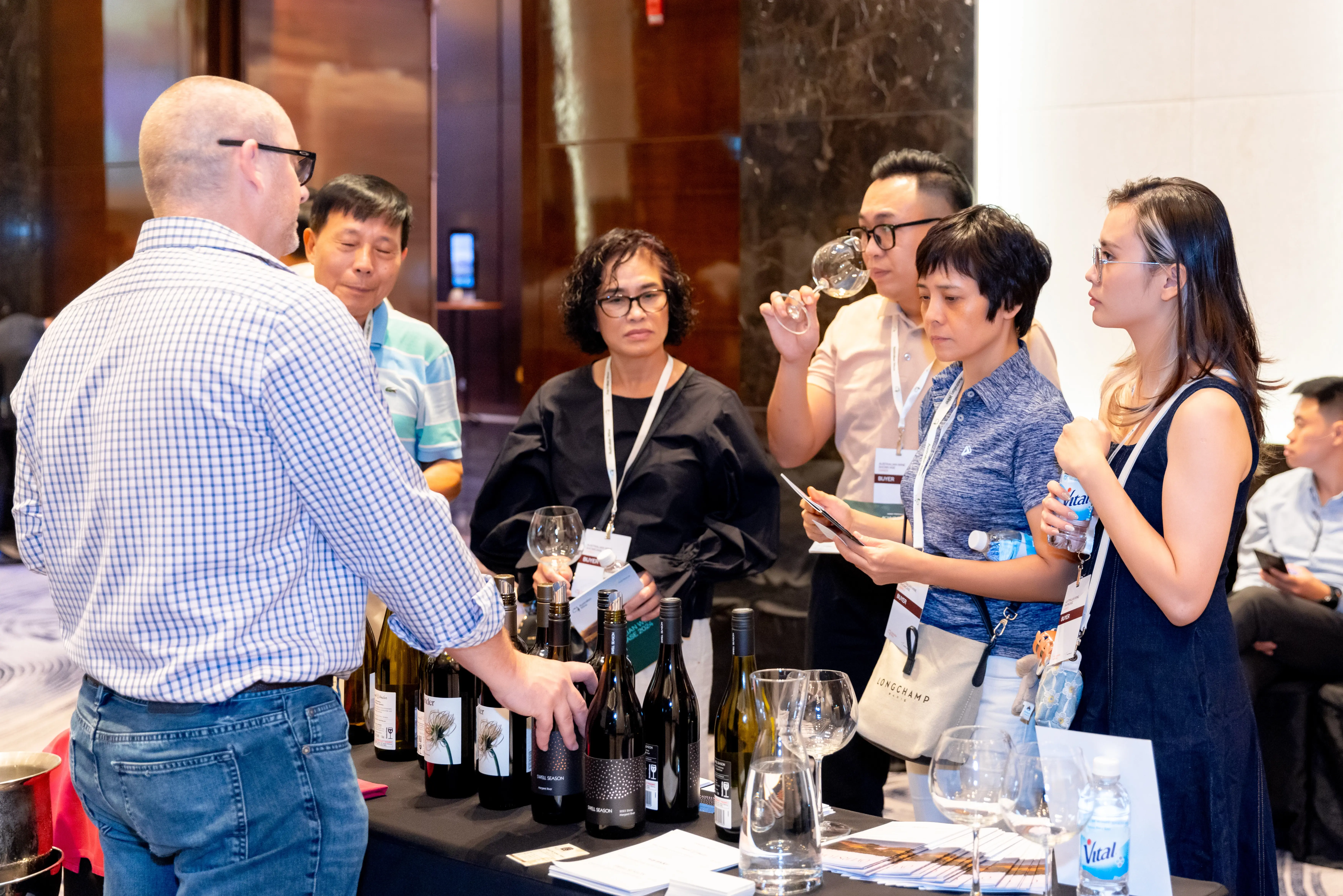 a group of people standing around a table with wine bottles
