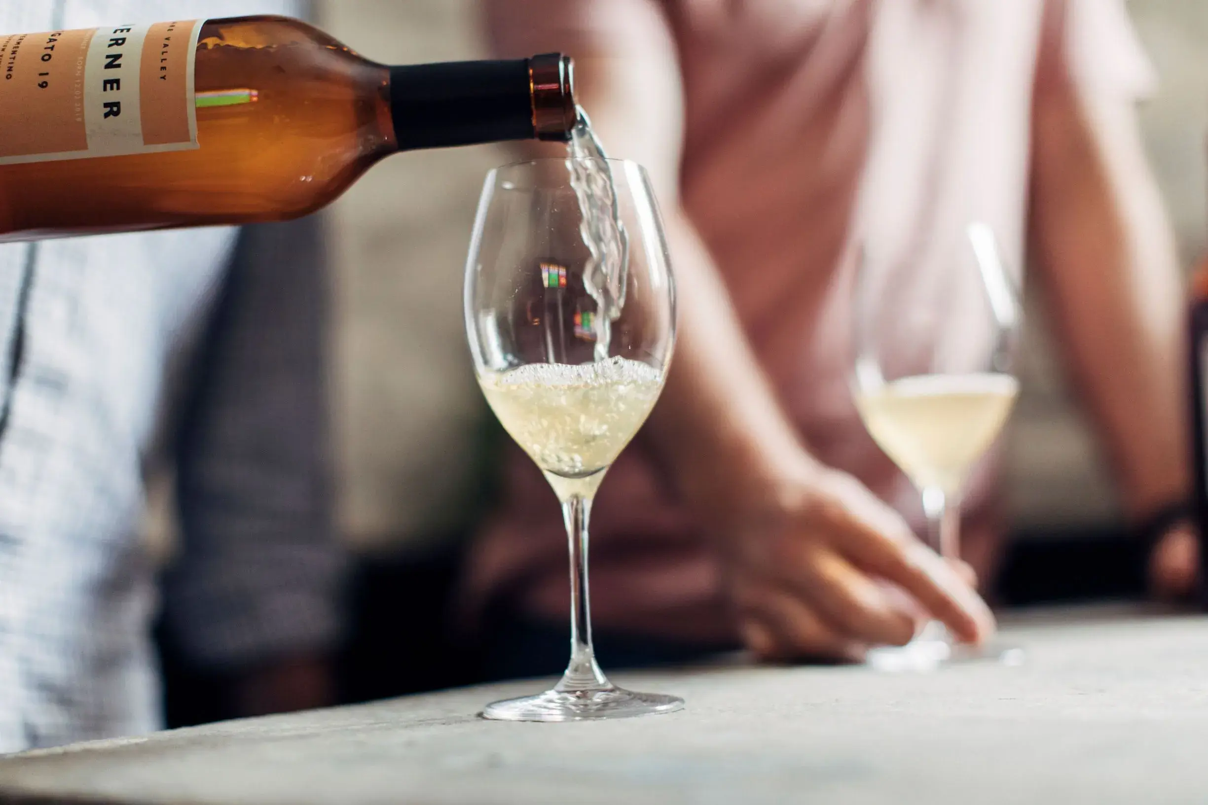a person pouring wine into a glass