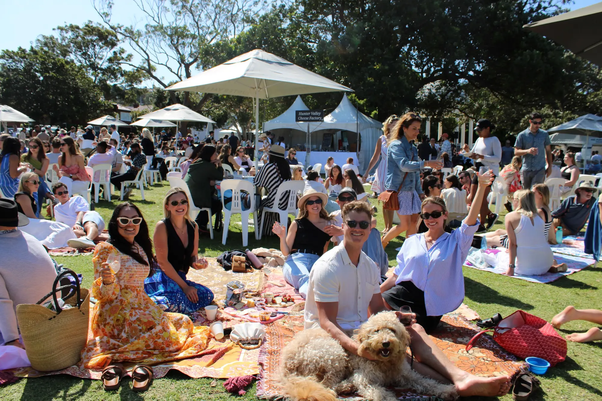 a group of people sitting on a blanket in a park