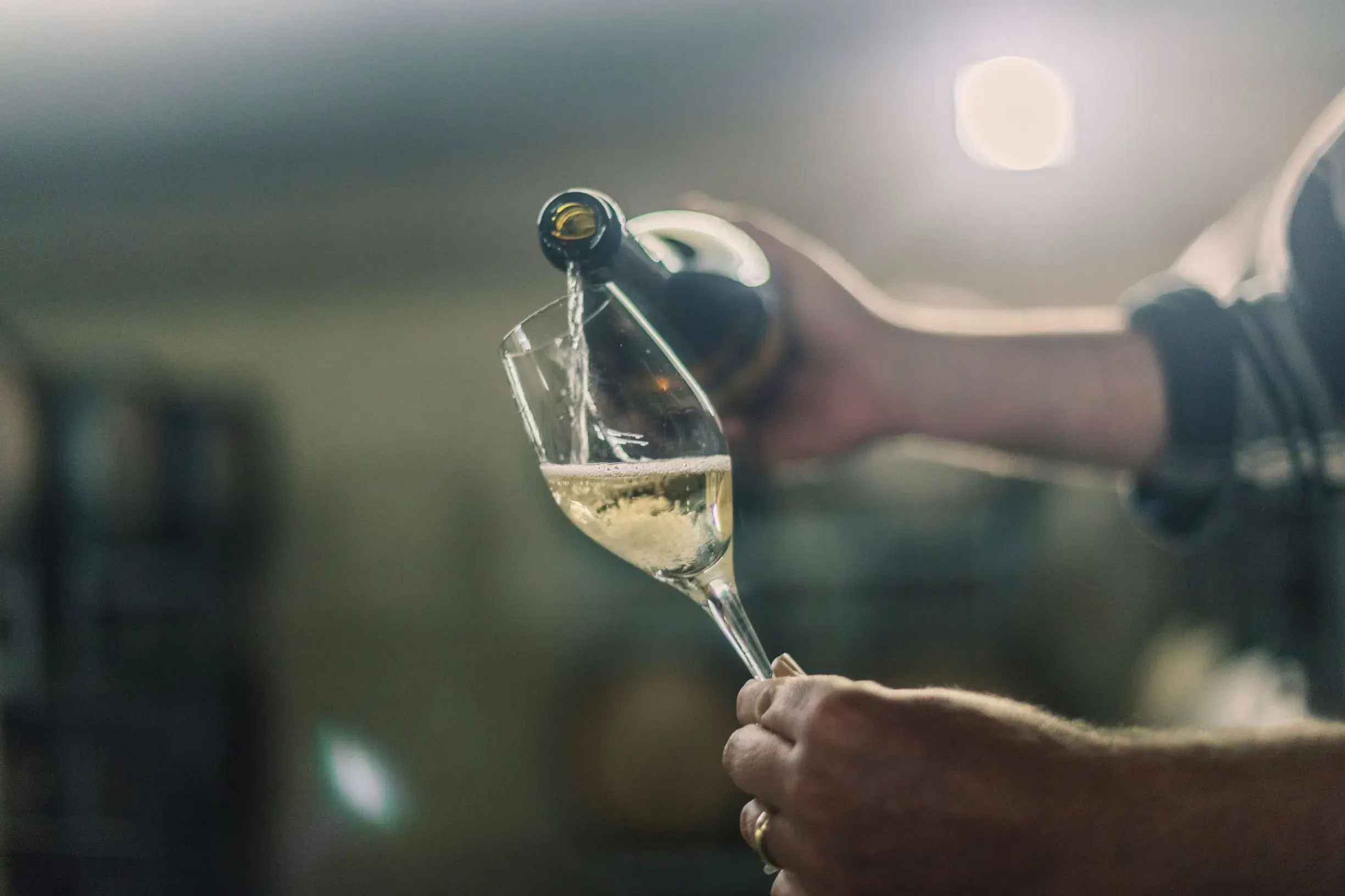 a person pouring a glass of wine