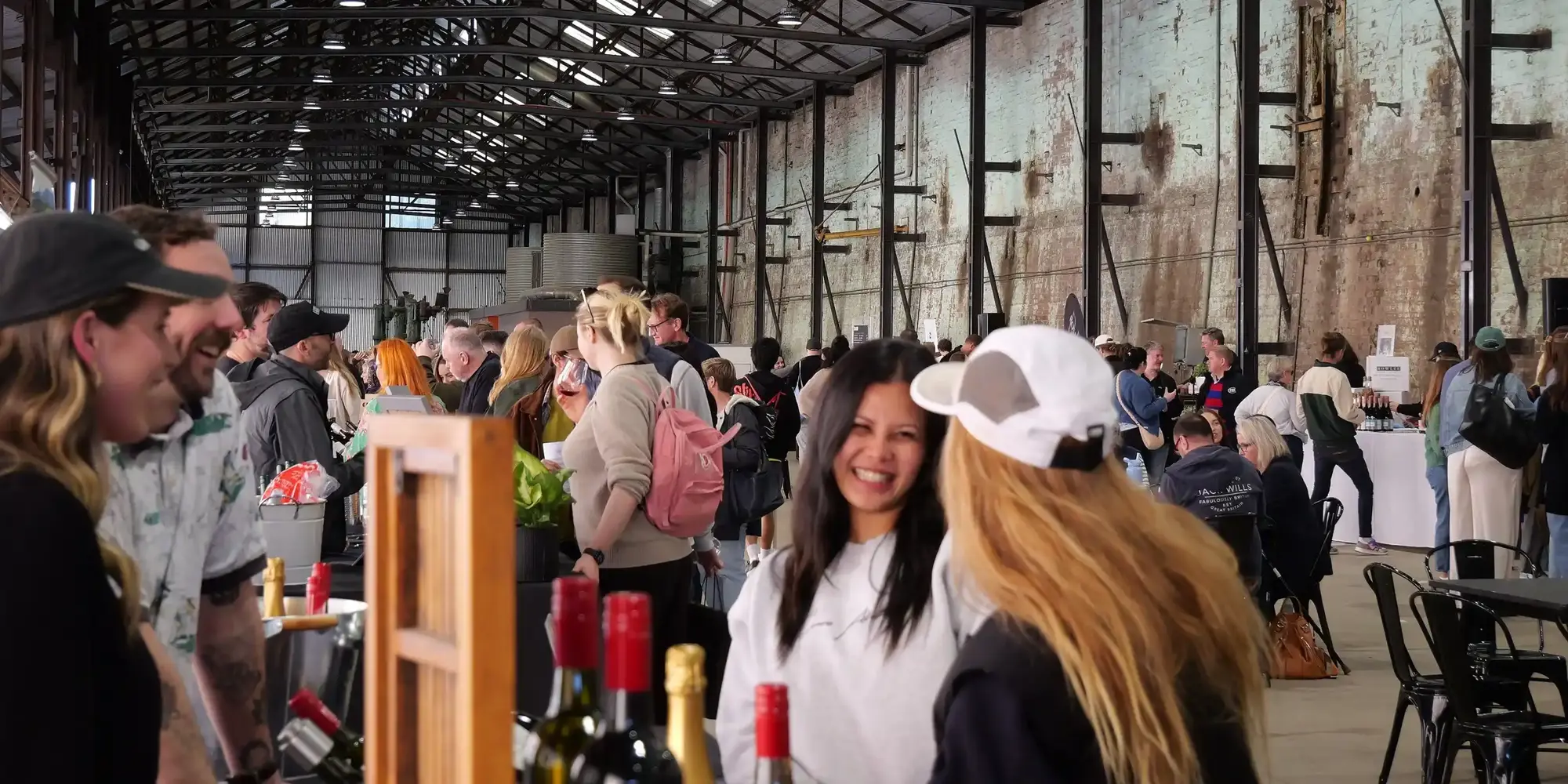a group of people standing in a room with bottles of wine