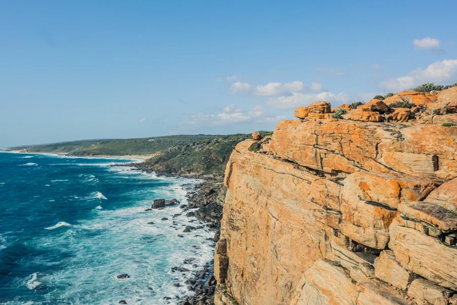 a rocky cliff with a body of water and blue sky