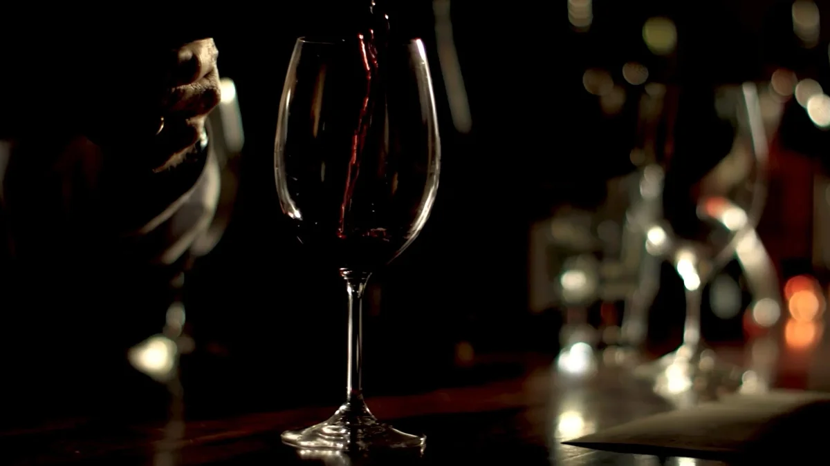 a person pouring wine into a glass